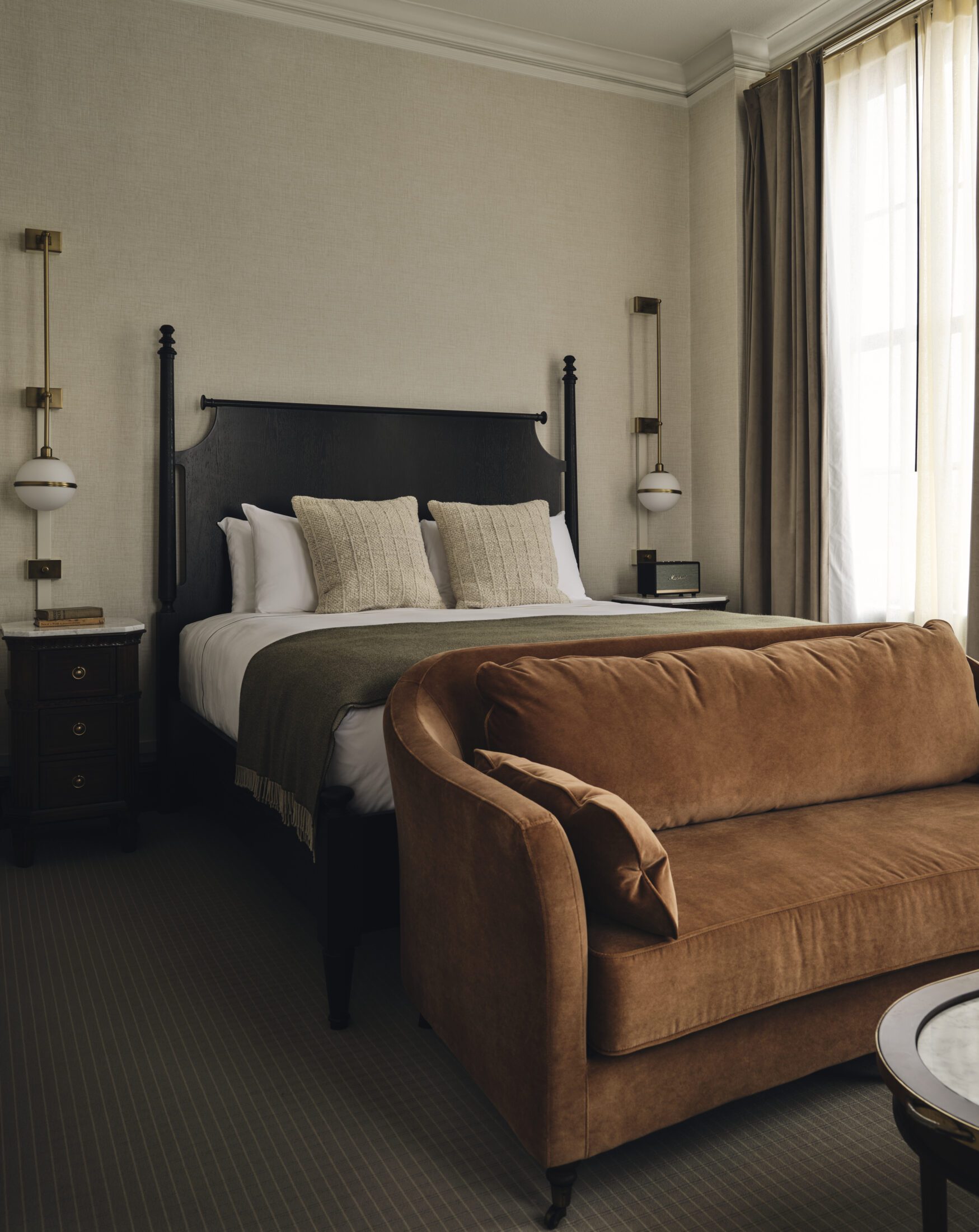 Hotel room with couch and large windows covered by sheer curtains