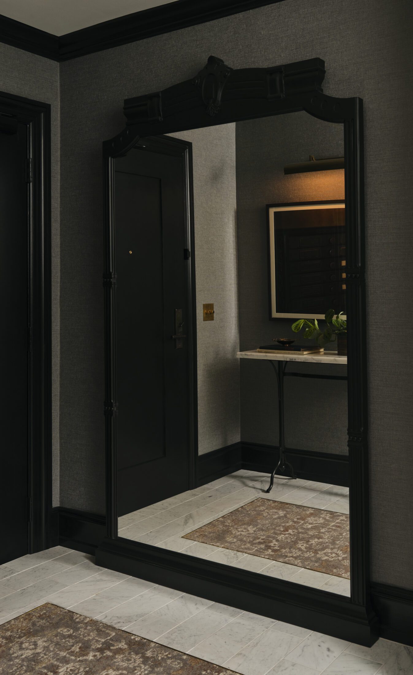 Large black framed mirror with entryway of hotel room in reflection